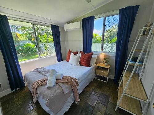 1 dormitorio con 1 cama con cortinas azules y escalera en Gateway to Paradise en Westcourt
