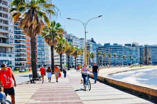 un grupo de personas caminando y montando bicicletas en la playa en Elegante apto en corazón Pocitos, en Montevideo