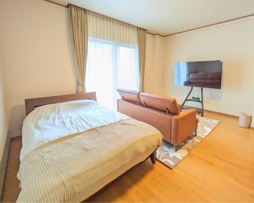 1 dormitorio con 1 cama, 1 silla y TV en The Global Tower, en Niihama