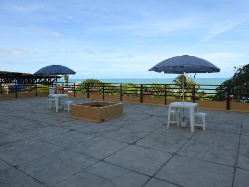 two tables and chairs with umbrellas on a patio at Apart Hotel Casa Grande in Natal