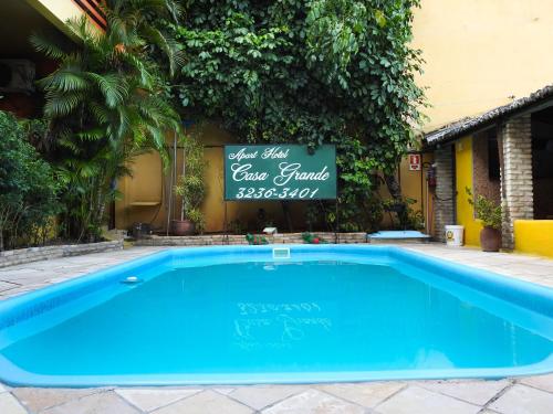 a swimming pool with a sign next to a building at Apart Hotel Casa Grande in Natal