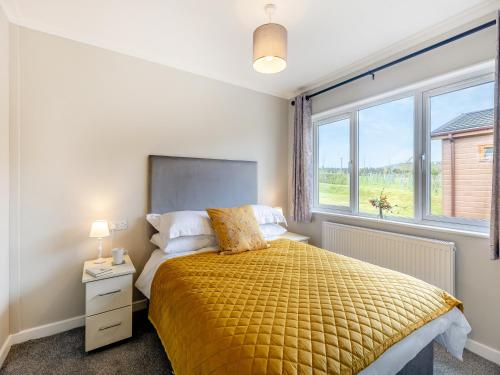 a bedroom with a bed with a yellow bedspread and a window at Winnal View - Uk46891 in Kinlet