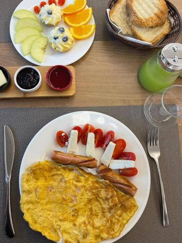 two plates of breakfast food with eggs sausage and fruit at Reign Hotel in Vorë