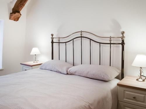 ein Schlafzimmer mit einem Bett mit weißer Bettwäsche und zwei Lampen in der Unterkunft Summerville Cottage in Kirkby Stephen
