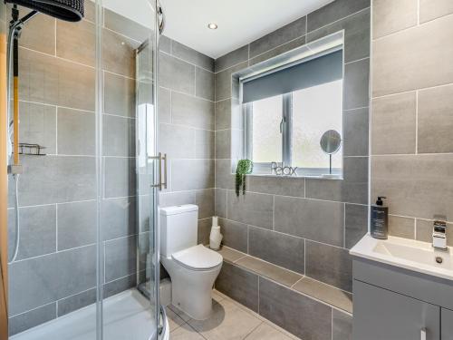 a bathroom with a toilet and a glass shower at Open Hearth Cottage in Cardiff