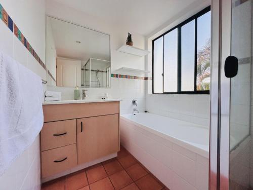 a white bathroom with a tub and a sink at Seaside Oasis 2Beds Apt with Free Parking in Gold Coast
