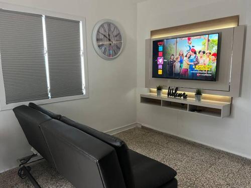 a living room with a couch and a flat screen tv at Villa Orquídea 4 in Humacao