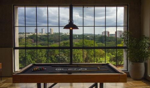 a pool table in front of a large window at Blend Coliving One - 2a in Ribeirão Preto