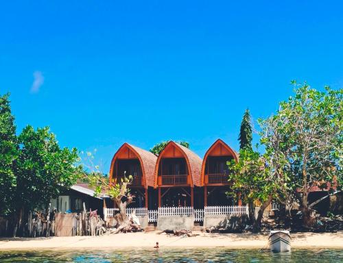 a building on a beach with trees and the water at Bunaken 18 Diving Resort and Cafe in Bunaken