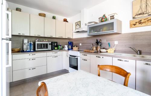 - une cuisine blanche avec des placards blancs et une table dans l'établissement Lovely Home In La Bernerie-En-Retz, à La Bernerie-en-Retz
