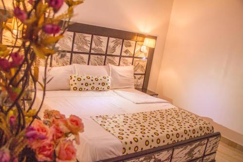 ein Schlafzimmer mit einem großen Bett mit weißer Bettwäsche und Blumen in der Unterkunft Francinesplace Hotel in Uyo