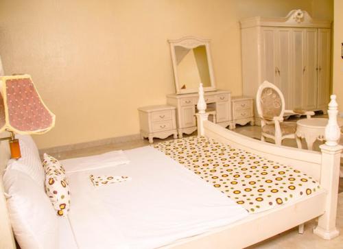 1 dormitorio con cama blanca y espejo en Francinesplace Hotel en Uyo