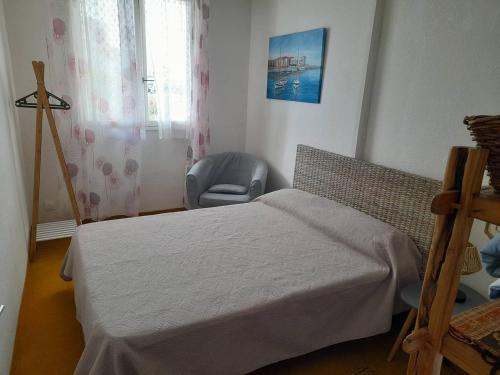 une chambre avec un lit, une chaise et une fenêtre dans l'établissement Charmant T2 à 100m de la plage avec terrasse, parking privé et animaux admis - FR-1-324A-62, à Saint-Hilaire-de-Riez