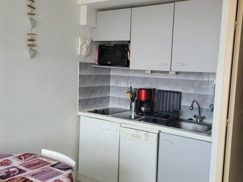 une petite cuisine avec un évier et un micro-ondes dans l'établissement Charmant F3 Mezzanine avec Piscine, Clim, Proche Plage et Centre - 4 Pers. - FR-1-559-35, à Palavas-les-Flots