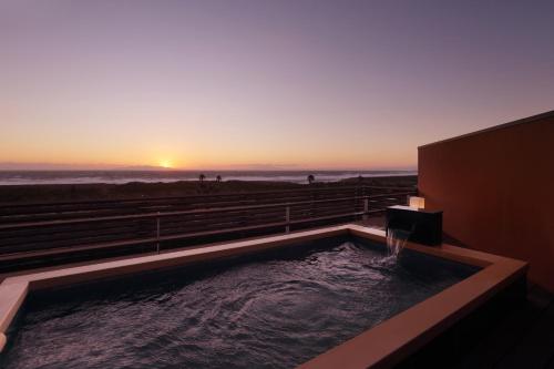 a hot tub with a sunset in the background at Senri no Kaze in Tateyama