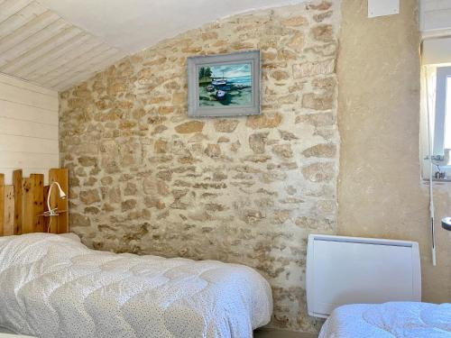 une chambre avec un mur en pierre avec un lit dans l'établissement Maison Rénovée Avec Jardin, Proche Océan et Commodités - FR-1-336-132, à Longeville-sur-Mer