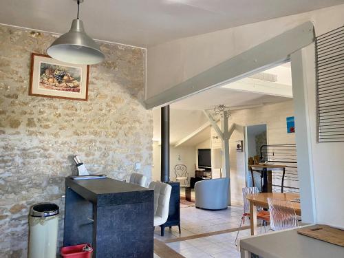 Il comprend une cuisine et un salon avec un mur en pierre. dans l'établissement Maison Rénovée Avec Jardin, Proche Océan et Commodités - FR-1-336-132, à Longeville-sur-Mer