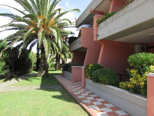 a pink building with a palm tree in front of it at Appartamenti Maricampo - HelloElba in Marina di Campo