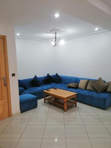 Sofá azul en la sala de estar con mesa de centro en Apparemment à louer, en Oujda