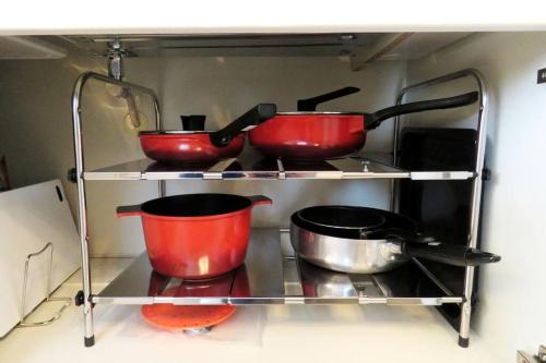 three red pots and pans on a shelf in a kitchen at Maizon de Aile Room A in Takasaki