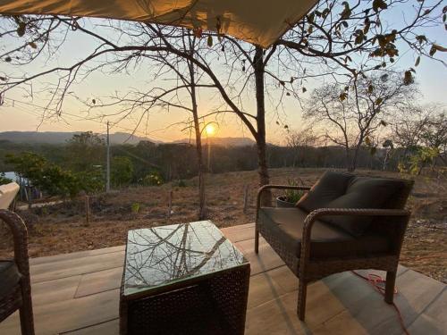 een patio met een stoel en een tafel en de zonsondergang bij Cozy Cottage on hilltop near Conchal - Casa Huella in Matapalo