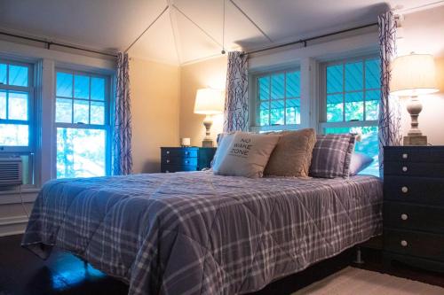 een slaapkamer met een bed met een blauwe deken en ramen bij The Old Stone Cottage at Tippy in North Webster