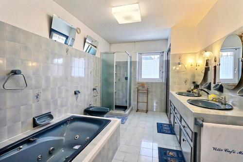 a bathroom with a tub and two sinks and a shower at Villa cafe marrec 8 in Port-Louis