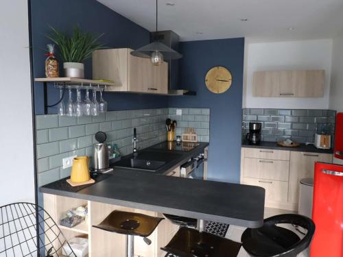 une cuisine avec un comptoir noir et des murs bleus dans l'établissement Appartement T2 à 300m du marché - Balcon, cuisine équipée, chambre confort, idéal vacances. - FR-1-494-183, à Royan