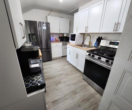 a kitchen with white cabinets and black appliances at Sports Retreat, Mins to Cedar Pt, Sports Force & Ferry, Private Deck, EV, Kids & Pet Friendly in Sandusky