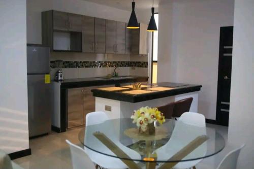 a kitchen with a glass table and white chairs at Sky Blue Apartments in Manta