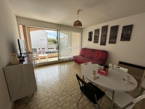 un salon avec une table et un canapé rouge dans l'établissement Appartement 2 pièces avec terrasse et garage, centre-ville Le Grau-du-Roi, 5 min de la plage - FR-1-250-266, au Grau-du-Roi