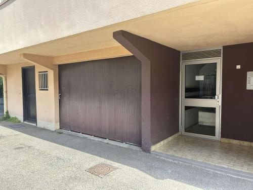 un bâtiment avec un garage marron avec une porte dans l'établissement Appartement 2 pièces avec terrasse et garage, centre-ville Le Grau-du-Roi, 5 min de la plage - FR-1-250-266, au Grau-du-Roi