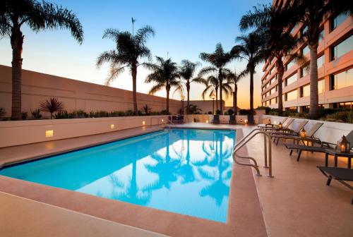 a swimming pool at a hotel with palm trees at The Westin Los Angeles Airport in Los Angeles