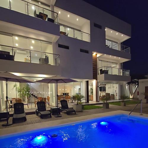 a house with a swimming pool in front of a building at Silver Inn Hotel in Cerro Azul