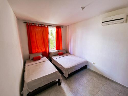 a room with two beds and a window with red curtains at Casa Campestre Laguna Verde in Villavicencio