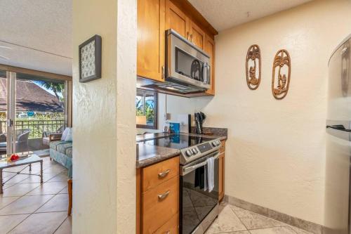a kitchen with a stove top oven next to a living room at Nani Kai Hale 208- Beachfront 1 bedroom 2 bathroom condo, oceanview in Kihei