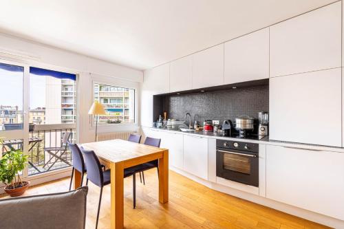 une cuisine avec des armoires blanches et une table et des chaises dans l'établissement GuestReady - Bright and airy in the 18th, à Paris