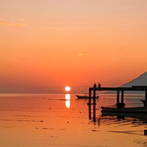 two people standing on a pier at sunset at Bunaken 18 Diving Resort and Cafe in Bunaken