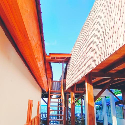a building with a wooden deck with a view of the ocean at Bunaken 18 Diving Resort and Cafe in Bunaken
