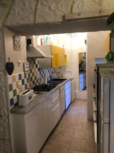 une cuisine avec des armoires blanches et des appareils bleus dans l'établissement La Bergerie, à Lauroux