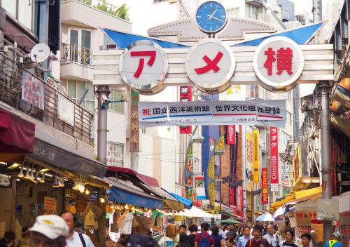 una folla di persone che camminano per una strada con dei cartelli di APA Hotel Ueno Ekikita a Tokyo