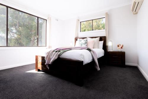 um quarto com uma cama com paredes e janelas brancas em Homely Hideaway with Parking & WiFi em Alanvale