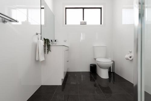 une salle de bain blanche avec toilettes et fenêtre dans l'établissement Homely Hideaway with Parking & WiFi, à Alanvale