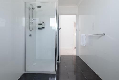 uma casa de banho com um chuveiro e uma porta de vidro em Homely Hideaway with Parking & WiFi em Alanvale