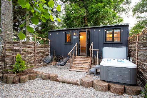 a small black tiny house with a hot tub at The Mar Huts - The Lomond Hut in Drymen