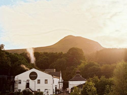 a white building with a mountain in the background at The Mar Huts - The Lomond Hut in Drymen
