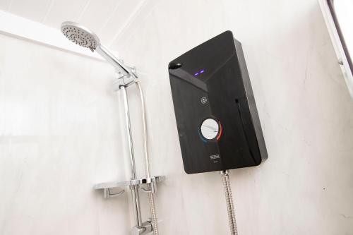 a bathroom with a shower with a speaker on the wall at The Mar Huts - The Lomond Hut in Drymen