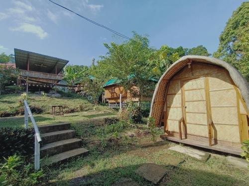 einen Pavillon auf einem Feld neben einem Haus in der Unterkunft Bon Joy's Transient House in Mabini