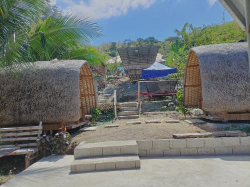 een achtertuin met twee rieten hutten en een tafel en trap bij Bon Joy's Transient House in Mabini