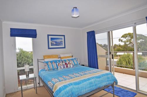 a bedroom with a bed with blue curtains and a balcony at The Esplanade 4 Free Wifi And Foxtel in Inverloch